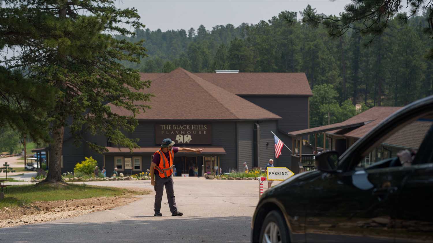 A man directs traffic in the parking lot of the Black Hills Playhouse